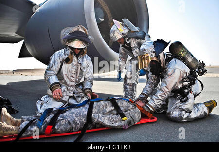 U.S. Air Force les pompiers du 379e Escadron de génie civil expéditionnaire sécuriser une victime simulée d'une planche dorsale au cours d'un exercice d'intervention en cas d'accident majeur, le 5 décembre 2011, en Asie du Sud-Ouest. L'exercice a été conçu pour tester la 379e escadre expéditionnaire aérienne aviateurs de capacité à répondre de façon appropriée à un accident d'avion. Airman Senior Paul Labbe Banque D'Images