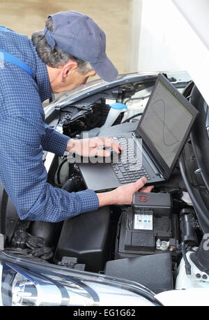 Une voiture mécanique avec ordinateur portable de diagnostic sur véhicule Banque D'Images