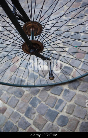 Roue en métal d'un vieux vélocipède sur une place pavée Banque D'Images