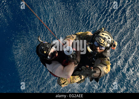 Un pararescueman, droit, aide Chef Master Sgt. Gerald Barnet alors qu'il est hissé dans un HH-60G Pave Hawk dans le cadre d'un exercice de sauvetage de l'eau 20 mars 2014, près du Camp Lemonnier, Djibouti. La formation leur a permis de séjour aviateurs compétents dans des compétences en sauvetage en mer. Le pararescueman est affecté à la 82e Escadron de sauvetage expéditionnaire. Barnet est l'enrôle conseiller avec la 449e groupe expéditionnaire aérienne. Le s.. Staci Miller Banque D'Images