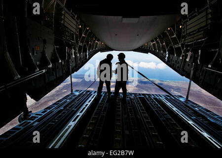 Dans le cadre de l'exercice RIMPAC 2008, l'enveloppe des jeux de guerre, les membres du 535e Escadron de transport aérien faire une goutte d'air d'une U.S. Air Force C17 Globemaster III cargo) sur Pohakuloa, New York, le 31 juillet 2012. La cargaison simule des palettes de "l'assistance humanitaire" que le rouleau de la rampe arrière de l'avion-cargo et parachute jusqu'au sol. Après la chute, arrimeurs, Senior Airman Jimmy Spillers ,à gauche, et Sgt. Brian Chewning jetez un oeil à l'arrière de l'avion. par Dennis l'APD. Banque D'Images