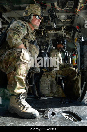 Un pararescueman et tactique de l'Armée de chien de détection d'explosifs sur un chien d'escorte et d'un HH-60G Pave Hawk au cours de la formation du 21 juin 2013, à l'aérodrome de Bagram, en Afghanistan. Chaque équipe et de chiens se relayaient pour porter les chiens près de l'hélicoptères pour les familiariser avec le son avant le levage. C'est la première fois que les deux branches ont participé à ce genre de formation ici. Le s.. Stephenie Wade Banque D'Images