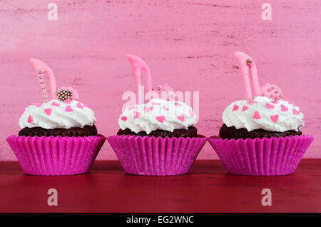 La Journée internationale des femmes, le 8 mars, cupcakes avec talon haut stiletto chaussures fondant sur fond de bois rose vintage. Banque D'Images