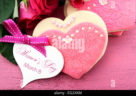 La Journée internationale des femmes, le 8 mars, les cookies en forme de coeur décorée en rose chers robes avec bouquet de roses roses Banque D'Images