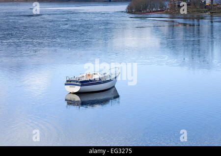 Petit bateau à moteur moderne ancrée sur Derwentwater, gelé en partie reflétée dans lac calme, hiver, Lake District, Cumbria England UK Banque D'Images