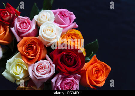 Bouquet de roses colorées contre surface sombre Banque D'Images