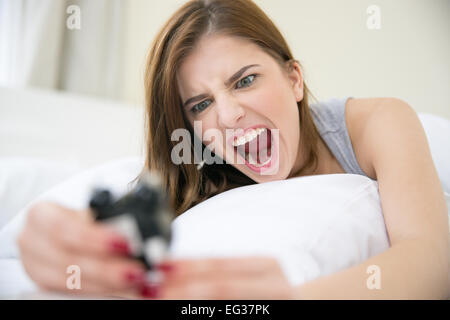 Femme en colère qui s'est réveillé très tôt pour appeler un réveil dans la chambre à coucher Banque D'Images