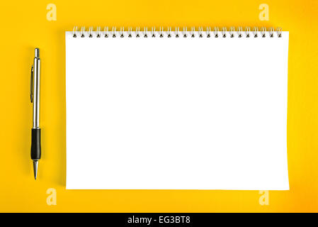 Stylo à bille et le papier blanc avec bloc-notes à Spirale en tant que copie d'affaires de l'espace sur fond jaune. Banque D'Images