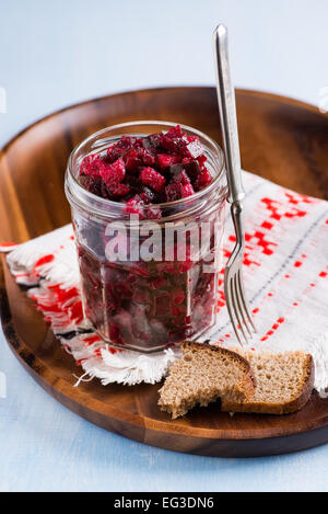 Salade de betterave russe dans un bocal en verre sur plateau en bois, fourchette et le pain de seigle, selective focus Banque D'Images