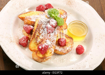 Pain perdu aux framboises et miel sur une plaque Banque D'Images