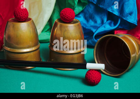 Accessoires de magie sur l'écran sur une table : tasses et des balles, des mouchoirs et de la baguette magique. Magiciens et illusionnistes Banque D'Images