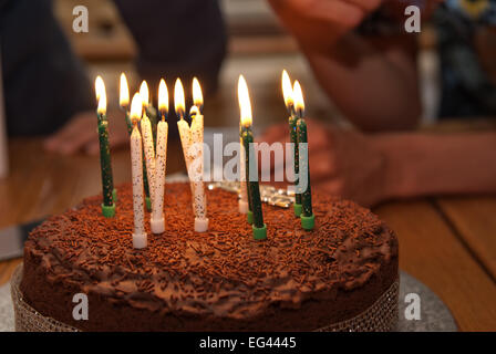 Treize brûler des bougies sur un gâteau d'anniversaire au chocolat maison recouvert de chocolat et de bonbons sprinkles Banque D'Images