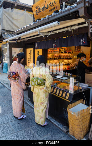 Habillé traditionnellement les femmes japonaises achetant quelques en-cas dans le quartier Higashiyama, Kyoto, Japon Banque D'Images