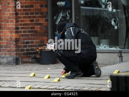 Copenhague, Danemark. Feb 15, 2015. Un agent de police fait enquête sur les trous de balle à l'Krudtoenden' centre culturel à Copenhague, Danemark, 15 février 2015. Photo : Britta Pedersen/dpa/Alamy Live News Banque D'Images