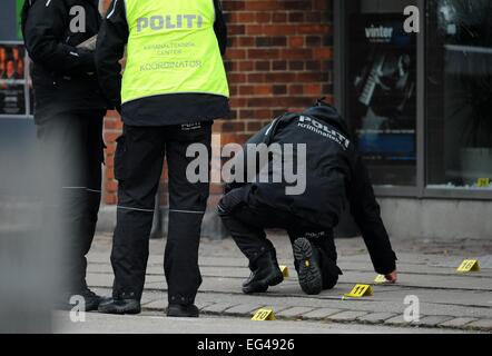 Copenhague, Danemark. Feb 15, 2015. Un agent de police fait enquête sur les trous de balle à l'Krudtoenden' centre culturel à Copenhague, Danemark, 15 février 2015. Photo : Britta Pedersen/dpa/Alamy Live News Banque D'Images