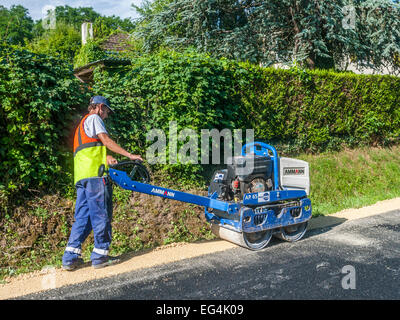 Travailleur et machine pour tasser les bord de la route - France. Banque D'Images