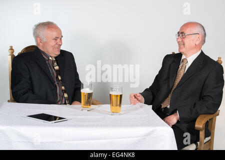 Deux heureux les hommes assis à la table avec de la bière Banque D'Images