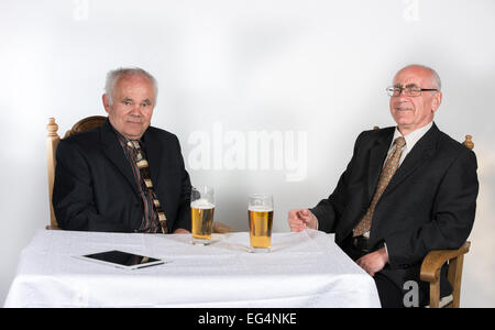 Deux heureux les hommes assis à la table avec de la bière Banque D'Images