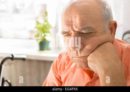 Close up haute grave homme chauve, en chemise orange, à la recherche vers le bas avec poing sur son visage Banque D'Images