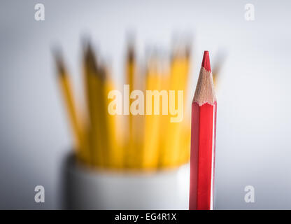 Un crayons rouge debout à partir d'un groupe de crayons de couleur jaune Banque D'Images