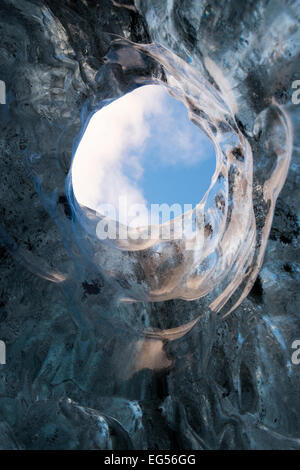Voir à travers un trou dans le ciel depuis l'intérieur d'une grotte de glace des glaciers du sud-est de l'Islande. Banque D'Images