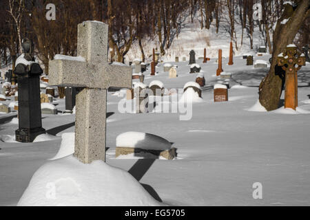 Pierres tombales couvertes de neige dans un cimetière américain avec une croix dans l'avant-plan Banque D'Images