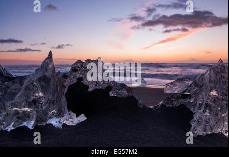 La glace de glacier échouée sur la plage de sable noir à Jokulsarlon en Islande. Banque D'Images