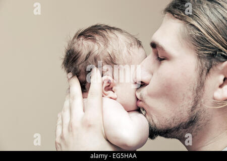 Père avec son jeune bébé de câliner et l'embrasser sur la joue. La paternité, l'amour. Banque D'Images