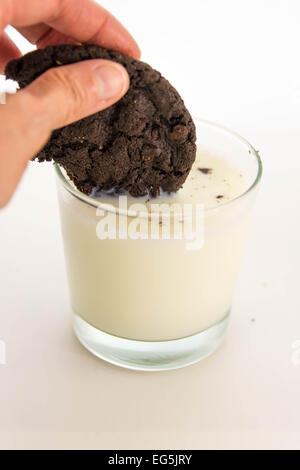 Chocolate cookie avec la main d'être trempés dans le lait Banque D'Images