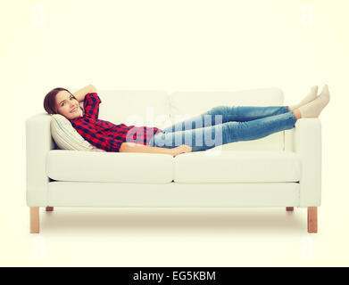 Smiling teenage girl lying on sofa Banque D'Images