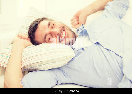 Smiling young man lying on sofa at home Banque D'Images