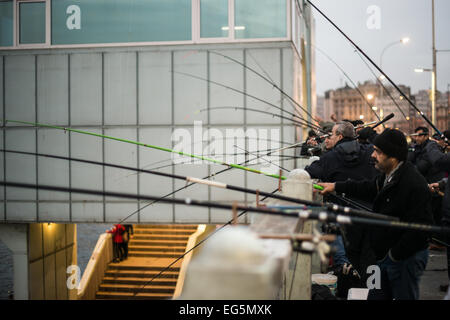 ISTANBUL, Turquie / Türkiye — les pêcheurs bordent le bord du pont de Galata avec leurs lignes sur le côté dans la Corne d'Or. Enjambant la Corne d'Or et reliant Eminonu à Karakoy, le pont de Galata est un pont à deux niveaux qui gère la circulation routière, tramway et piétonne au niveau supérieur avec des restaurants et des bars au niveau inférieur. Banque D'Images