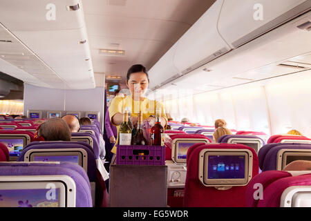 Une hôtesse de l'air, servant des boissons sur un vol de Thai Airways International de Londres à Bangkok Banque D'Images