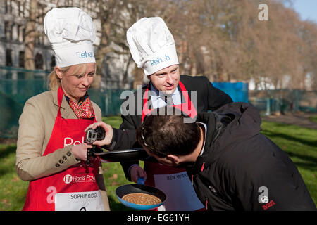 Sophie Ridge Sky news présentateur a un appareil photo placé sur son poêle avant la course de crêpes parlementaire députés,2015. Banque D'Images