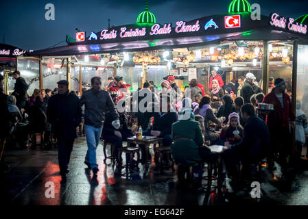 Balik Ekmek sandwichs de poisson Eminonu Istanbul Turquie // ISTANBUL, Turquie — des bateaux de pêche éclairés servent des balik ekmek (sandwichs de poisson) traditionnels le long du front de mer d'Eminonu, à la base du pont de Galata. Le balik ekmek est une cuisine de rue turque populaire composée de poisson grillé servi dans du pain frais, généralement préparé et vendu directement à partir de ces restaurants flottants. Le quartier d'Eminonu est une zone commerciale historique sur la Corne d'Or qui a servi de centre de transport et de commerce majeur pendant des siècles. La tradition culinaire au bord de l'eau perpétue une pratique qui remonte aux Generati Banque D'Images