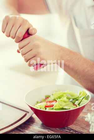 Les mains de l'assaisonnement dans un bol à salade Banque D'Images