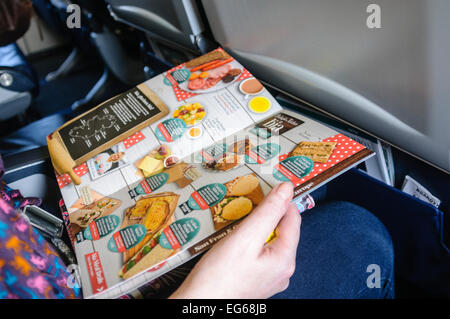 Une femme lit le menu en vol sur un avion Banque D'Images