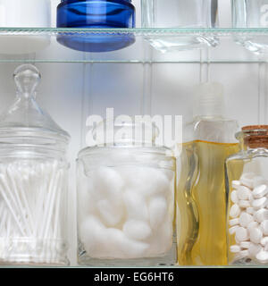 Libre de deux étagères d'une armoire à pharmacie. Une bouteille de comprimés, boules de coton et des tampons de coton et un assortiment de verres et bouteilles o Banque D'Images