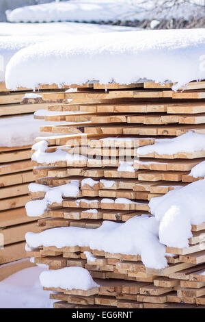 Pile de planches sciées couverte de neige. Arrière-plan de scierie Banque D'Images