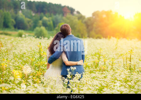 Young happy wedding couple hugging in the meadow back to camera Banque D'Images