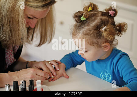 Maman blonde peinture ongles de sa fille Banque D'Images