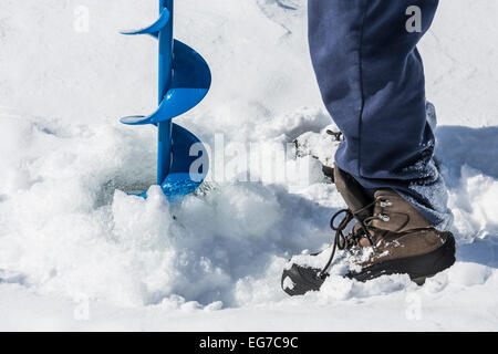 Percez un trou pour la pêche sur glace avec une vis sans fin de la glace sur un lac d'environ 12' de glace, près de Stanwood dans la Central Michigan, USA Banque D'Images