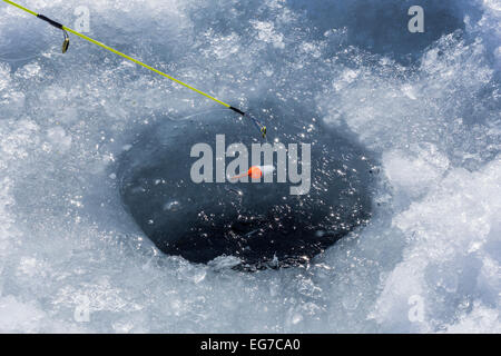 La pêche sur glace pour les crapets dans un trou sur un lac dans le centre de Michigan, USA Banque D'Images