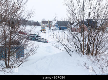 Chasse-neige labourer une rue de banlieue dans une ville nord-américaine après une tempête de neige. Banque D'Images