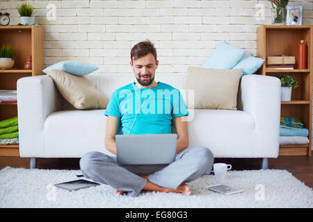 Beau gars dans les tenues de l'aide de gadgets modernes à la maison Banque D'Images