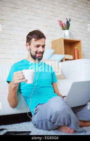 Beau gars dans les tenues de l'aide de gadgets modernes à la maison Banque D'Images