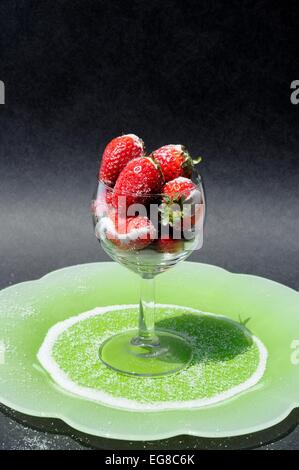 Fraises fraîches dans un verre a pied avec du sucre saupoudré sur top Banque D'Images