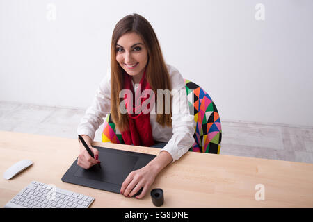 Femme heureuse de travailler sur tablette graphique in office Banque D'Images