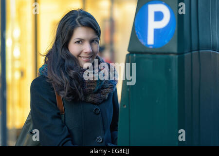 Smiling woman élégant en ville aux côtés d'un distributeur automatique de billets Banque D'Images