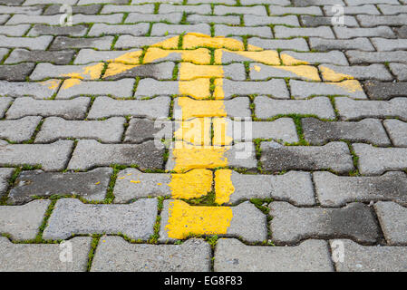 Flèche jaune peint sur pavés gris, route en direction de signer Banque D'Images